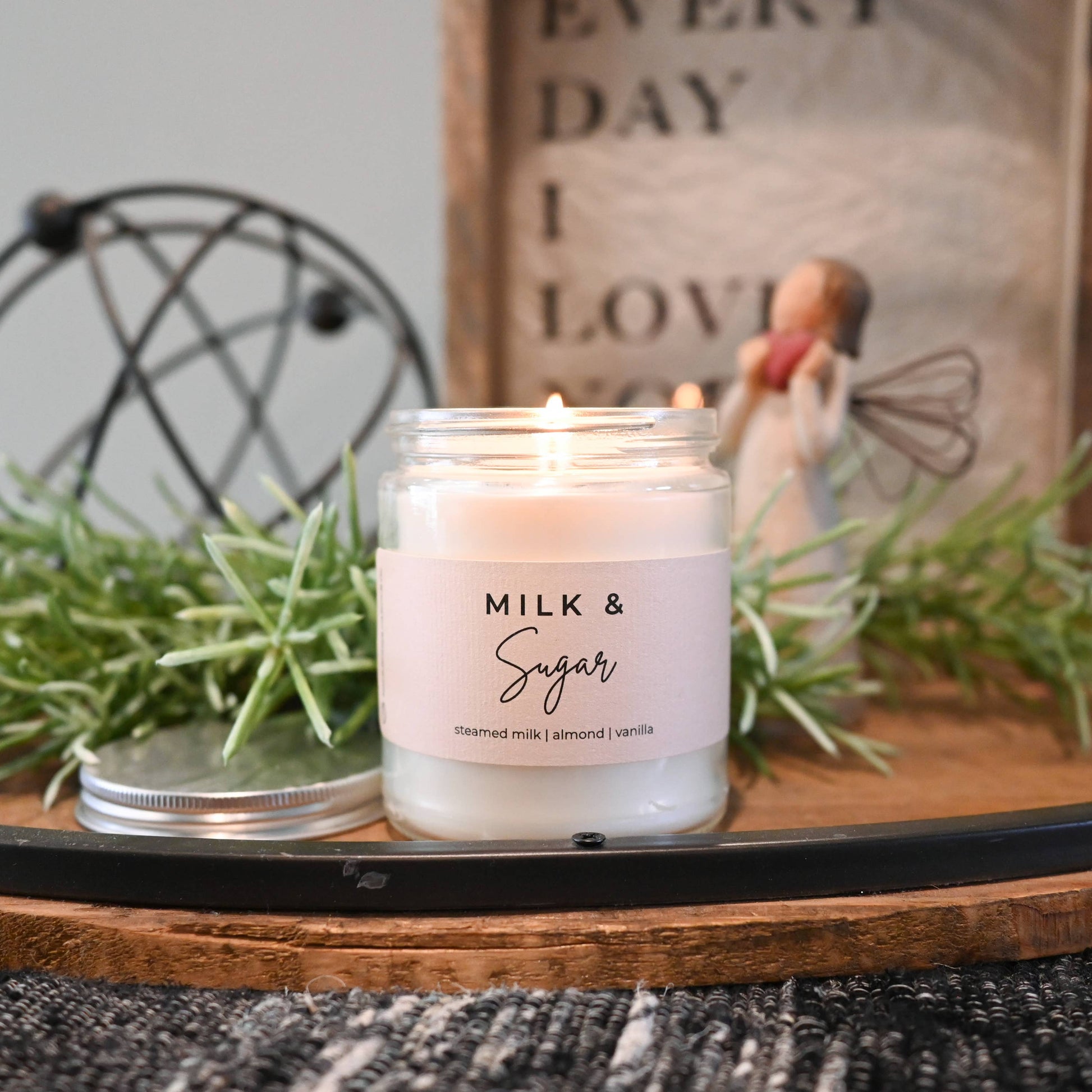 Candle labeled 'Milk & Sugar' on a wooden tray with decorative elements.