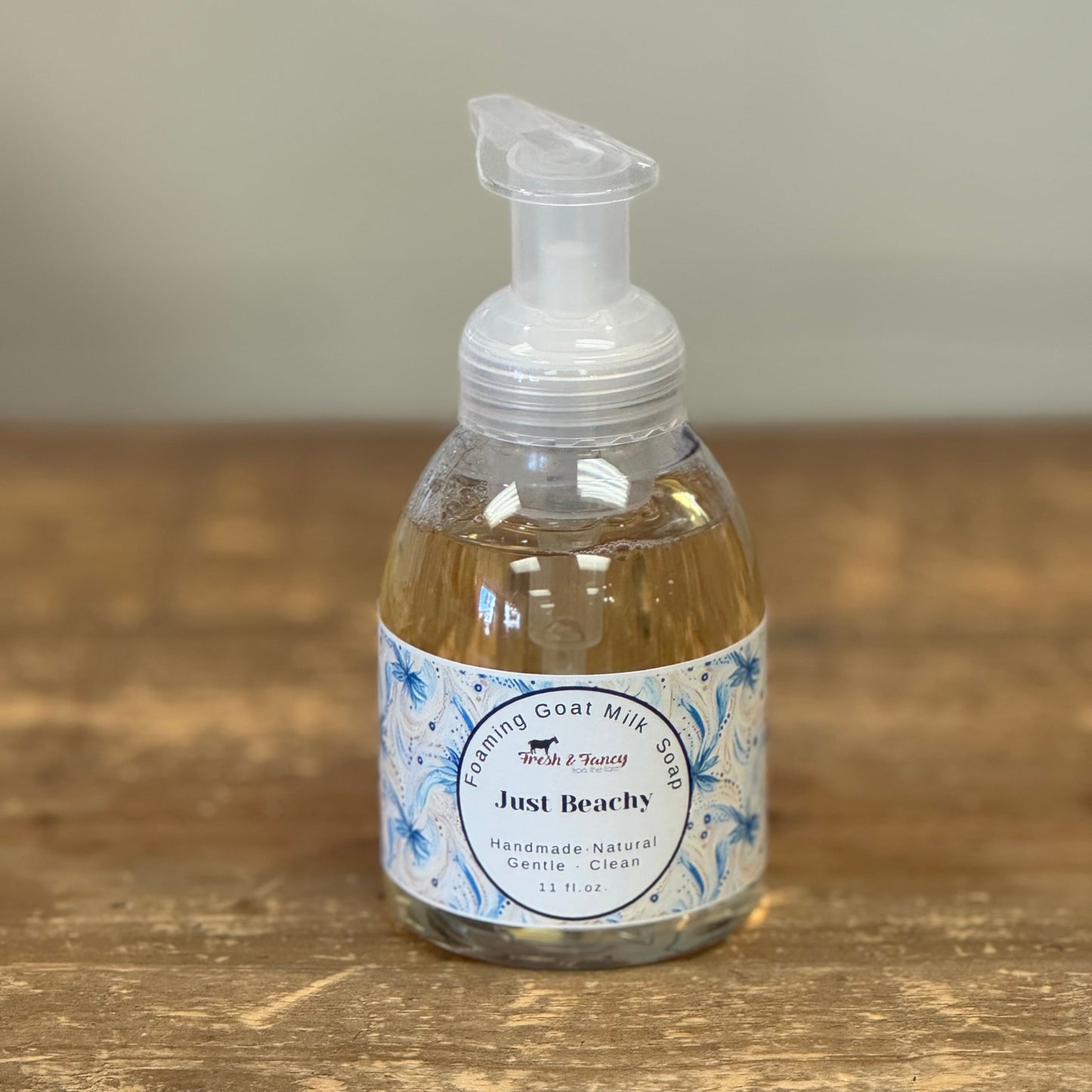 Clear pump bottle with beach themed label wrapped around the bottle
