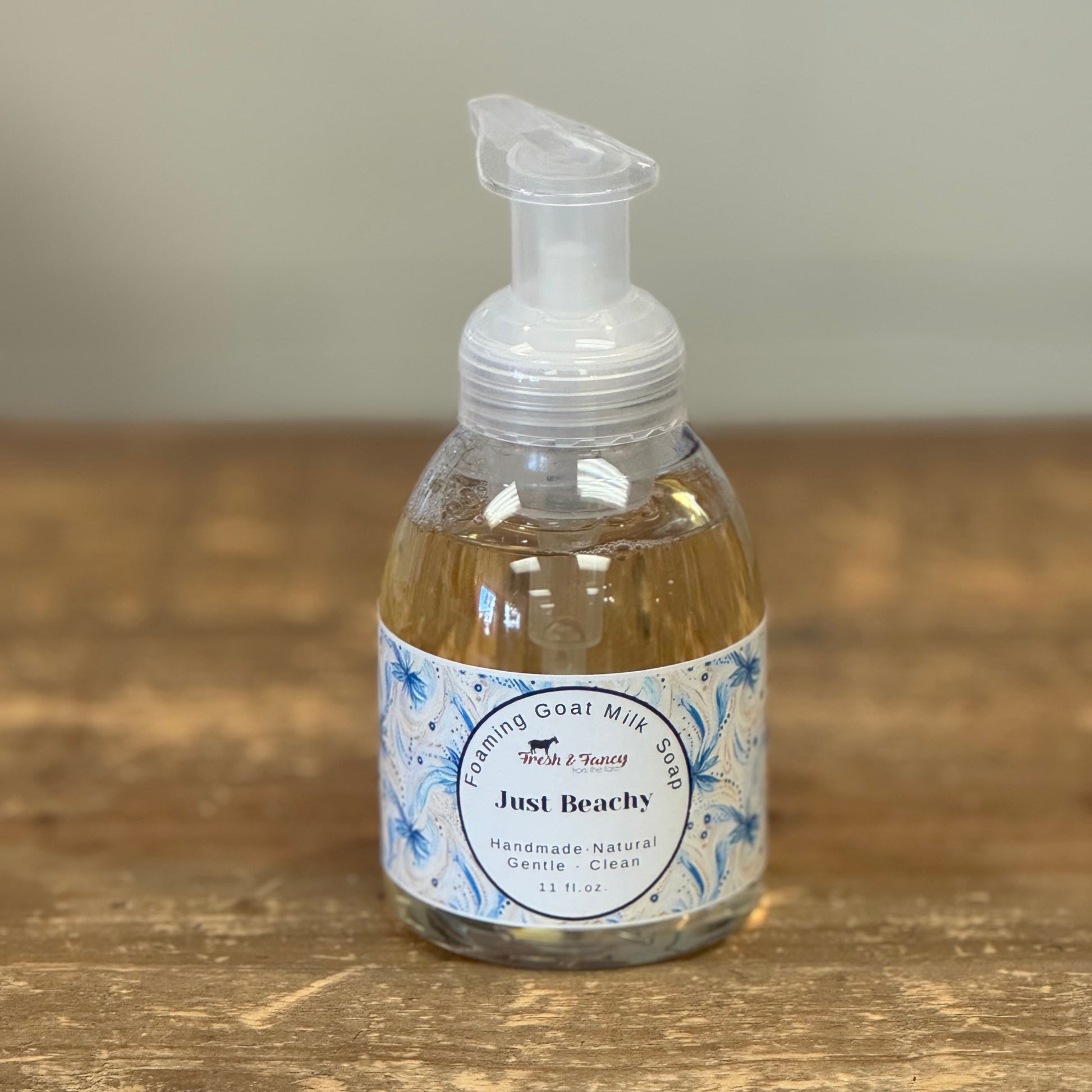 Clear pump bottle with beach themed label wrapped around the bottle