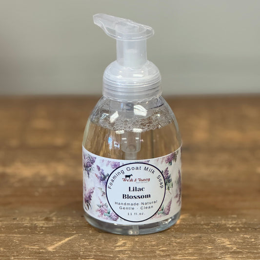Clear bottle and a white label with purple lilac blossoms all over it. 