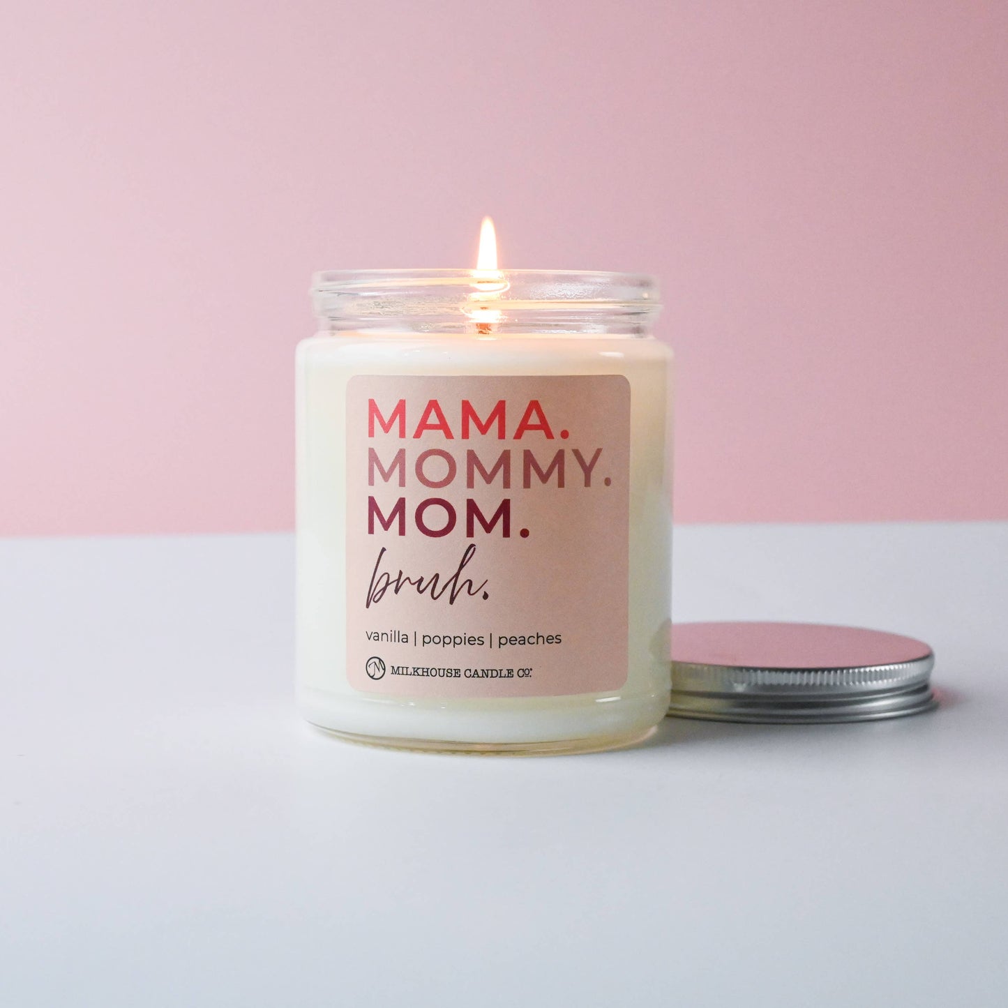Candle with 'MAMA. MOMMY. MOM.' text on a pink and white background