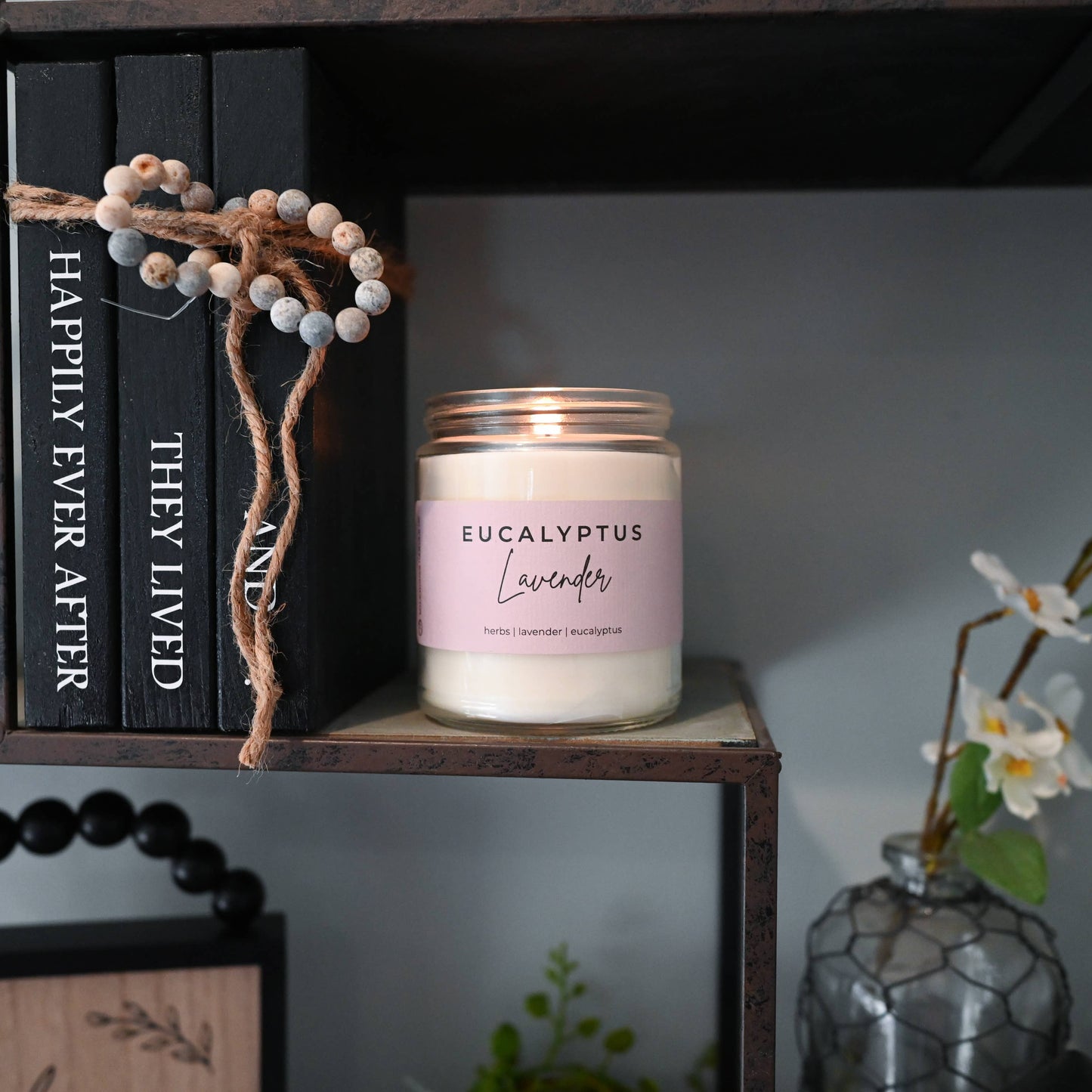 Candle labeled 'Eucalyptus Lavender' on a shelf with decorative items